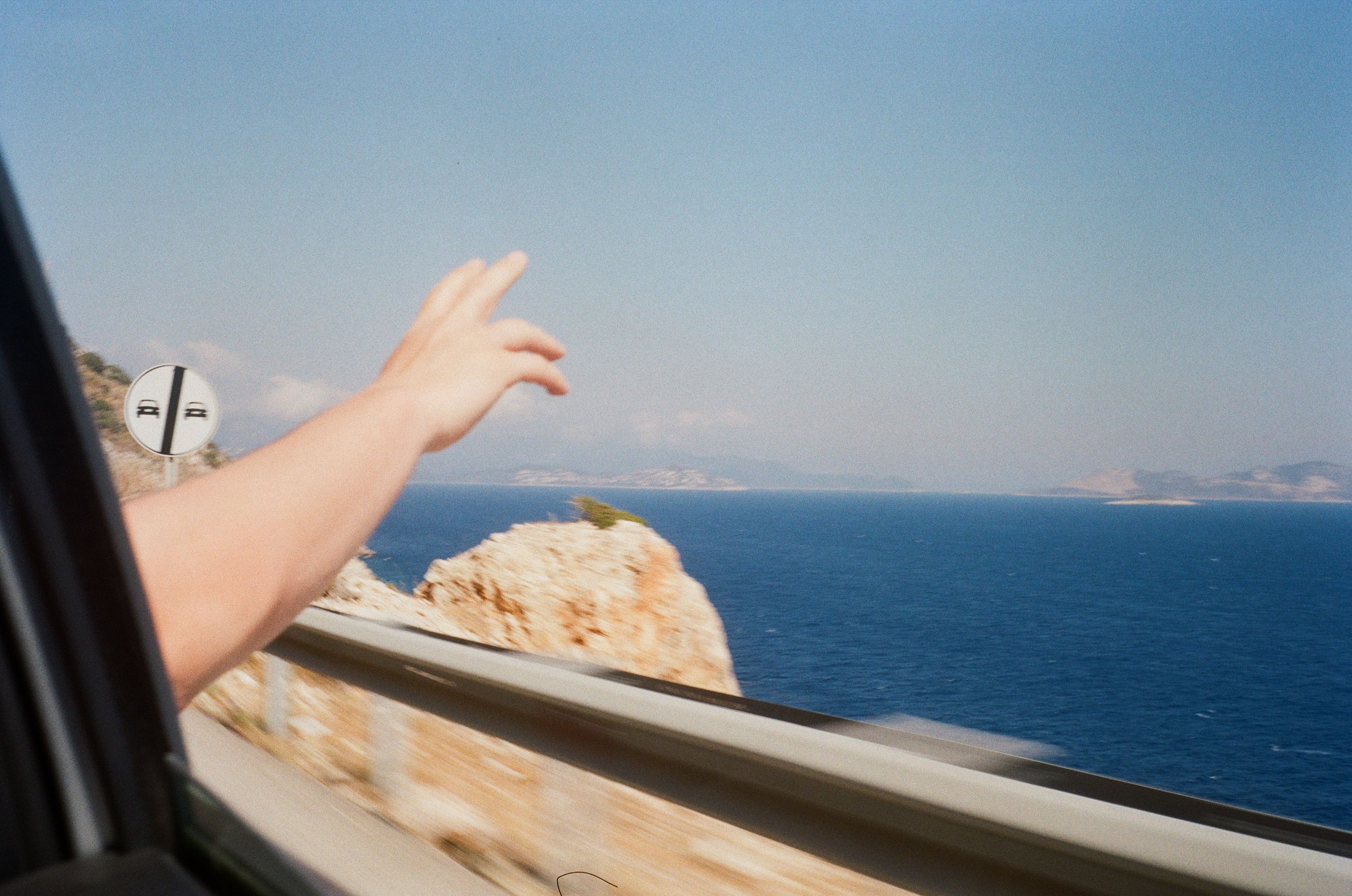 A car ride showcasing a hand making a peace sign against a stunning ocean view. - Photo by Olesia Sydorenko on Pexels