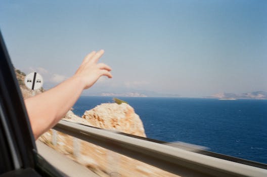 A car ride showcasing a hand making a peace sign against a stunning ocean view.