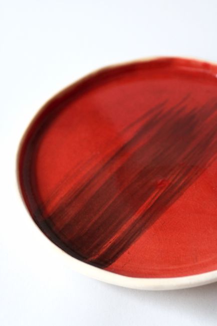 Close-up of a red ceramic plate showcasing artistic brush strokes, ideal for design inspiration.