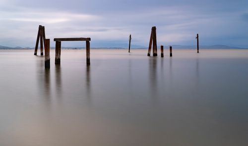 Free Peaceful seascape featuring long exposure and wooden posts in calm waters. Stock Photo