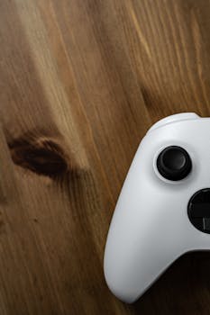 Close-up of a sleek white gaming controller on a wooden surface, ideal for tech enthusiasts.