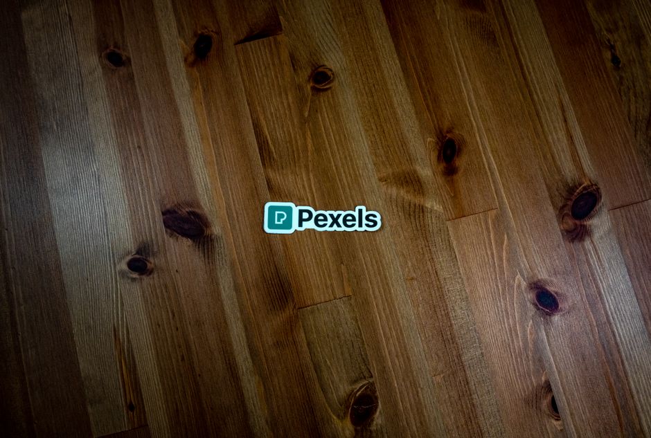 A rustic wooden surface featuring a Pexels logo sticker, ideal for branding or design purposes.