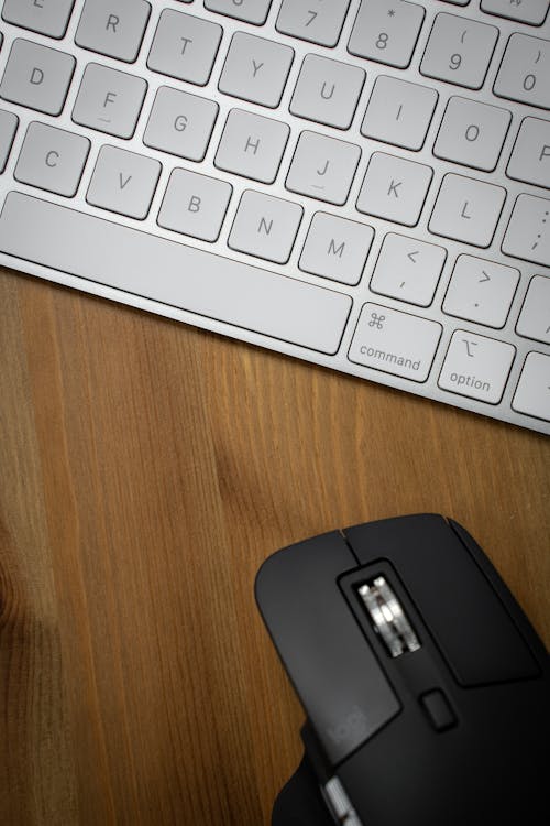 A Black Computer Mouse Near a White Keyboard