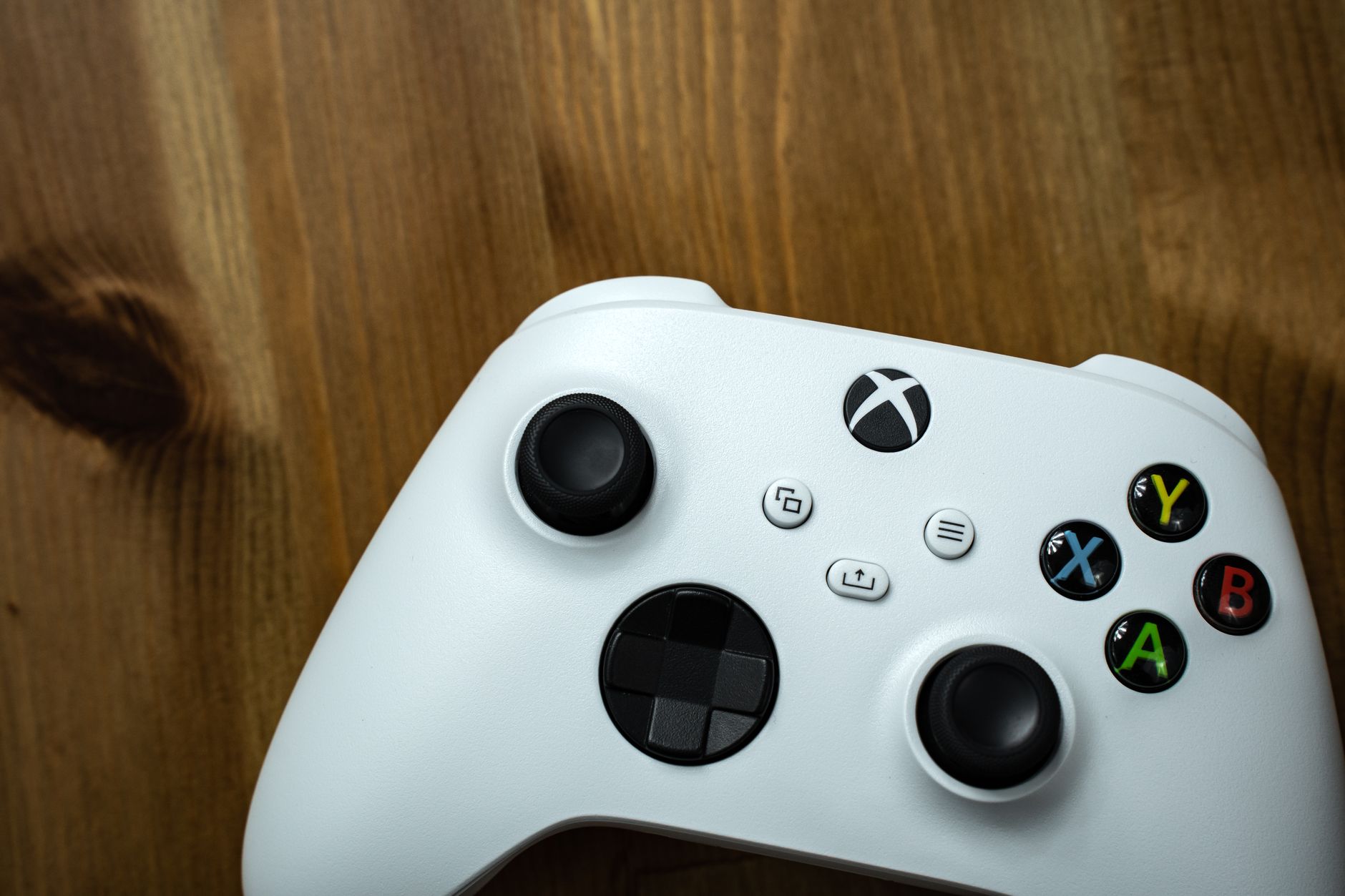 Close-up of a white game controller on a rustic wooden surface.
