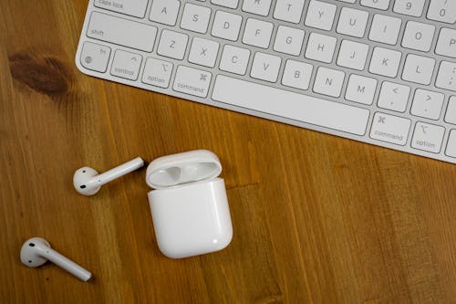 Free Close-Up Shot of Airpods beside a White Keyboard Stock Photo