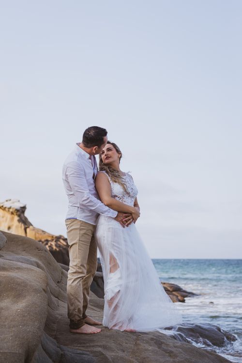 Free A romantic couple embracing on a seaside cliff, showcasing love and togetherness near the ocean. Stock Photo