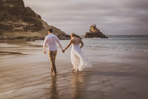 Free A Romantic Couple Walking on the Beach Stock Photo