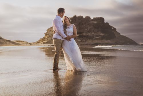 Free A romantic couple embraces on a scenic beach at sunset, celebrating love. Stock Photo