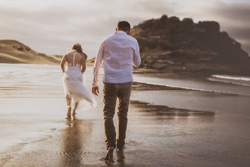 A Couple Walking Barefoot at the Beach