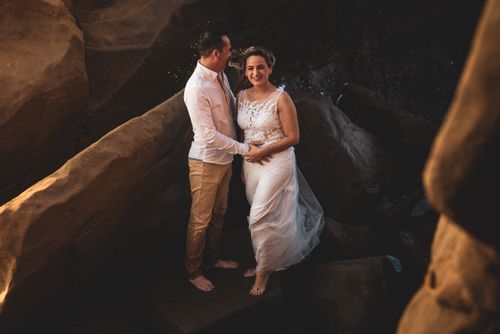 Free A romantic couple embracing on a rocky beach, capturing love and connection against a natural backdrop. Stock Photo
