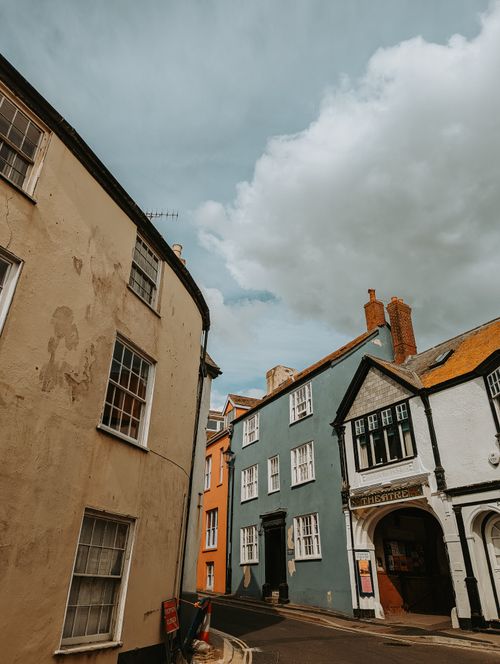 Free Explore a quaint historical street lined with colorful buildings under a dramatic sky. Stock Photo