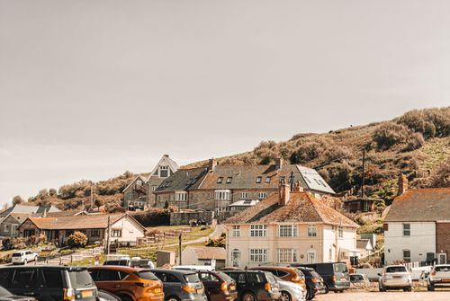 Free Picturesque seaside village with parked cars and charming houses along a hillside. Stock Photo