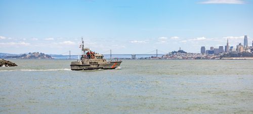 Free A military boat cruising in the San Francisco Bay with the city skyline and Bay Bridge in the background. Stock Photo