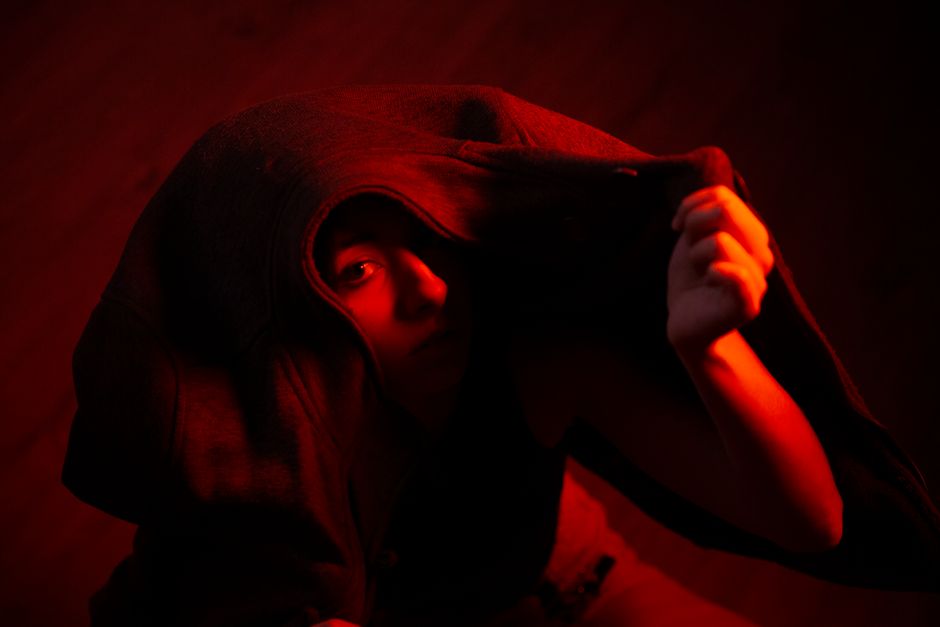 A mysterious portrait of a person under dramatic red lighting, evoking intrigue and intensity.