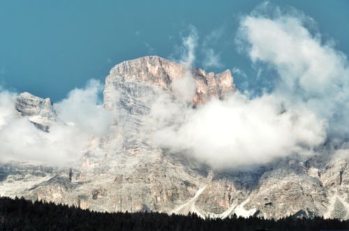 Free A breathtaking view of rocky mountain peaks enveloped by clouds against a bright blue sky. Stock Photo