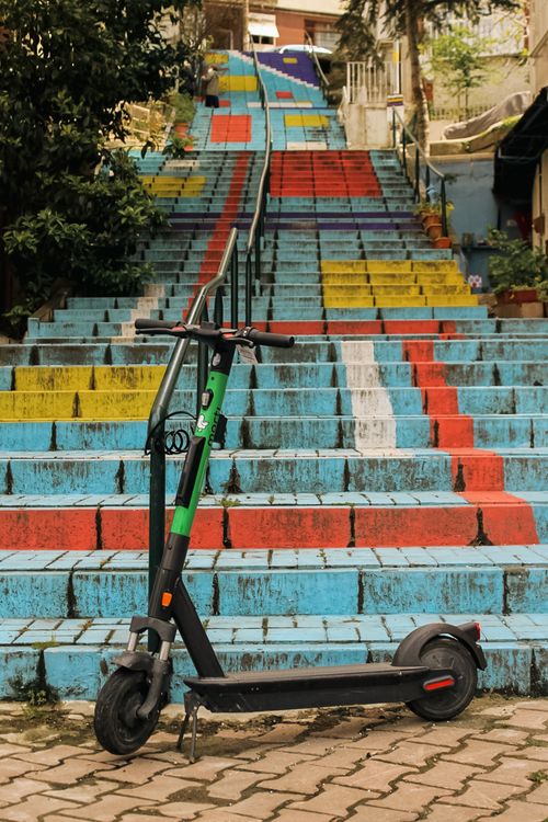 Free Electric scooter parked in front of vibrant painted stairs in Istanbul, Turkey. Stock Photo