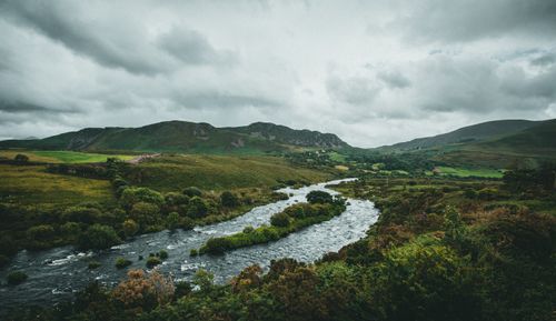 Free Majestic mountain landscape featuring a winding river under a cloudy sky, creating a serene natural scene. Stock Photo