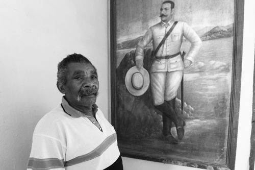 Free Black and white portrait of a man beside a historical painting, showcasing cultural heritage. Stock Photo