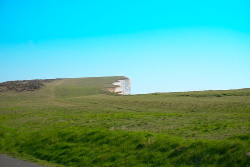 Free Scenic view of Eastbourne's white cliffs with lush green grass and a clear blue sky. Stock Photo