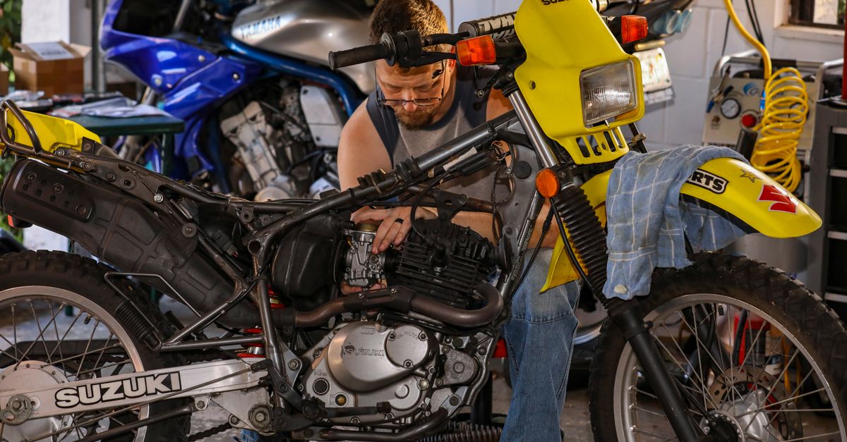 Foto de moto en Mechanic repairing a Suzuki motorcycle in a cluttered garage, focusing on engine maintenance. · ServiMotriz Villavicencio