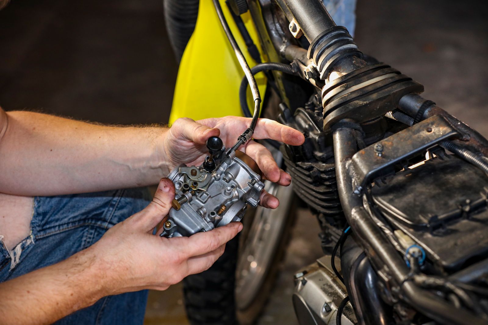 Gros plan sur les mains d'un mécanicien réparant un carburateur de moto