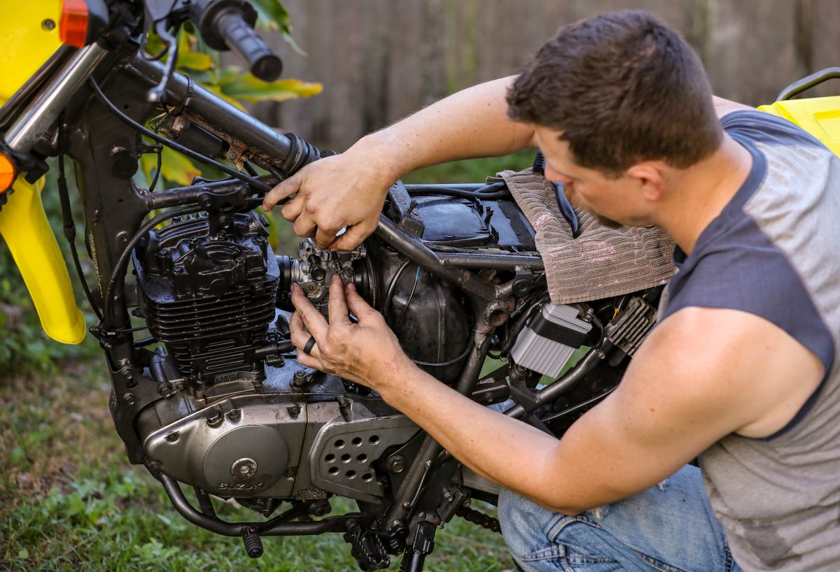 A mechanic working on an open motorcycle engine