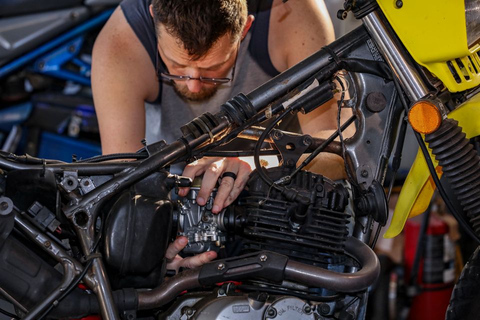 Pria memperbaiki sepeda motor di garasi