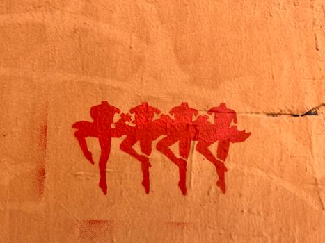 Stencil art of three dancers on a peach-colored textured wall in Saint Petersburg, Russia.