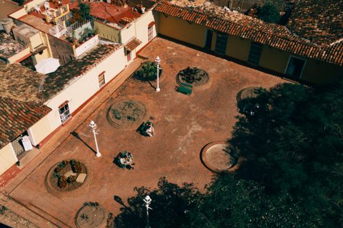 Free High angle view of a peaceful rustic courtyard with benches, tiled roofs, and greenery. Stock Photo