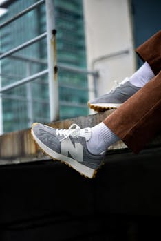 Close-up of feet in sneakers on a balcony railing, showcasing urban style in Kuala Lumpur.