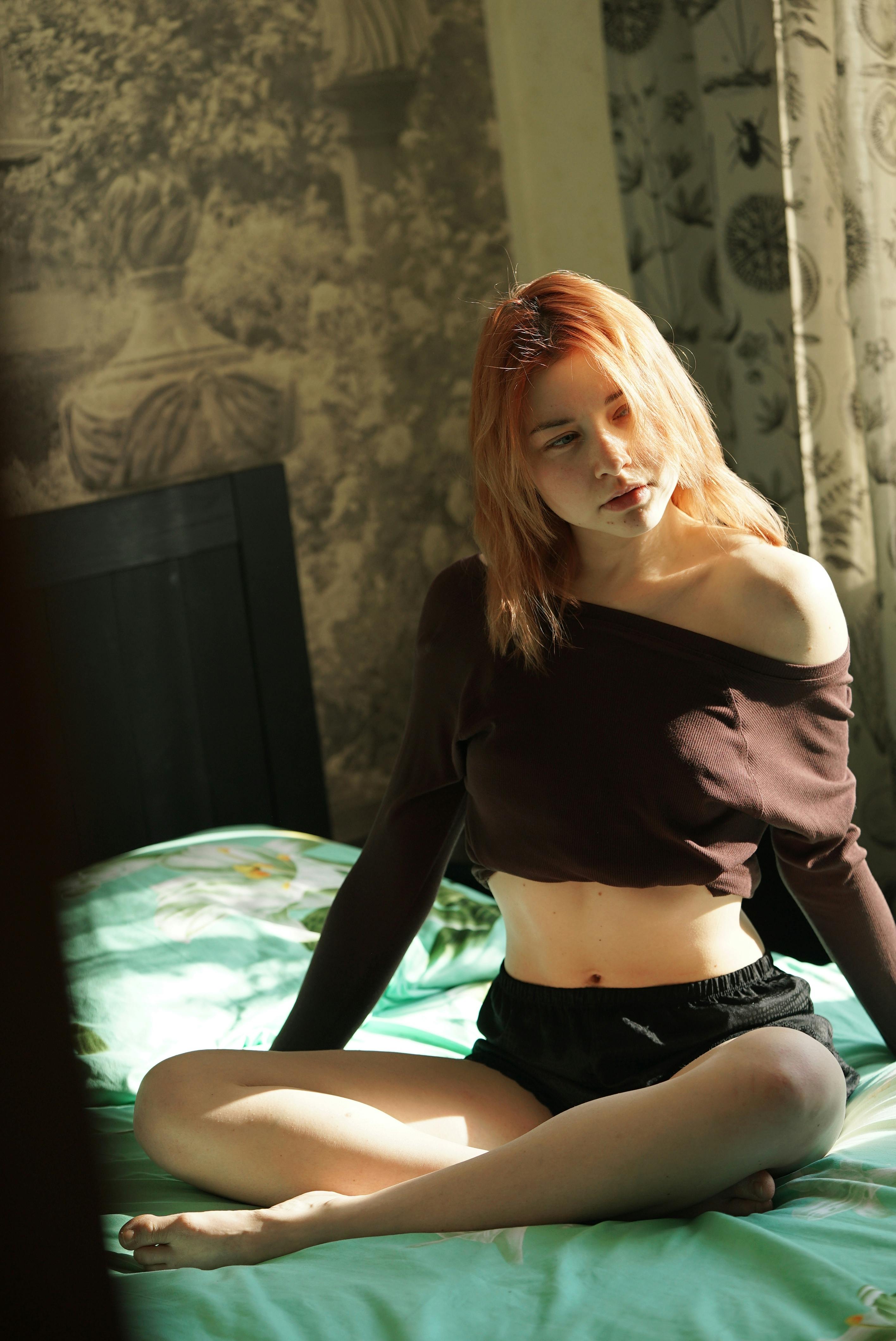 бесплатная Женщина, сидящая на кровати  Стоковое фото