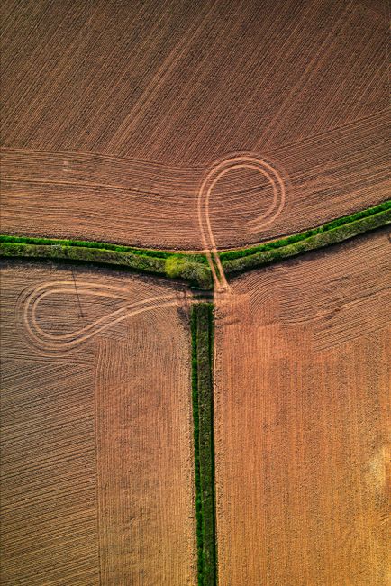 Drone shot of vast farm landscapes with intricate tire patterns in Aylesbeare, England.