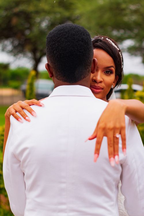 Free A bride and groom share an affectionate embrace outdoors, focusing on the bride's ring. Stock Photo