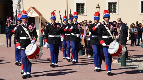 Free Royal guards in vibrant uniforms parade with drums during a ceremonial march outdoors. Stock Photo