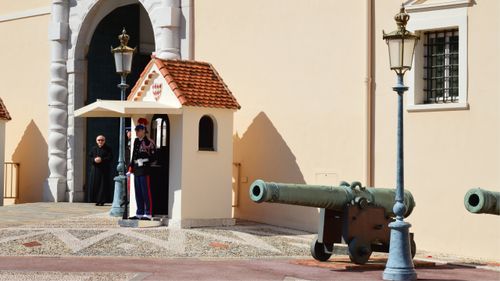Free A traditional guard in uniform stands at a palace entrance beside historic cannons. Stock Photo