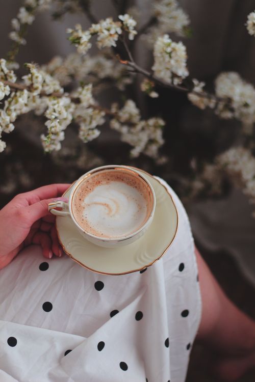 Free A serene moment of enjoying coffee in nature, surrounded by blossoms. Stock Photo