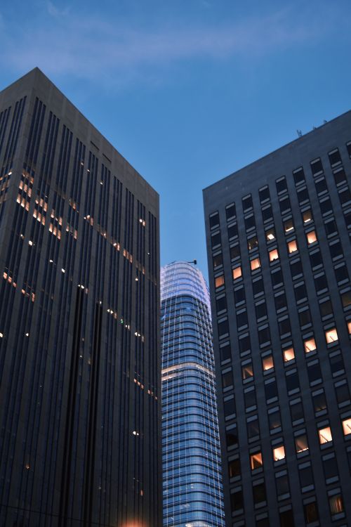 Free San Francisco high rises at dusk with lit windows against a blue sky. Stock Photo