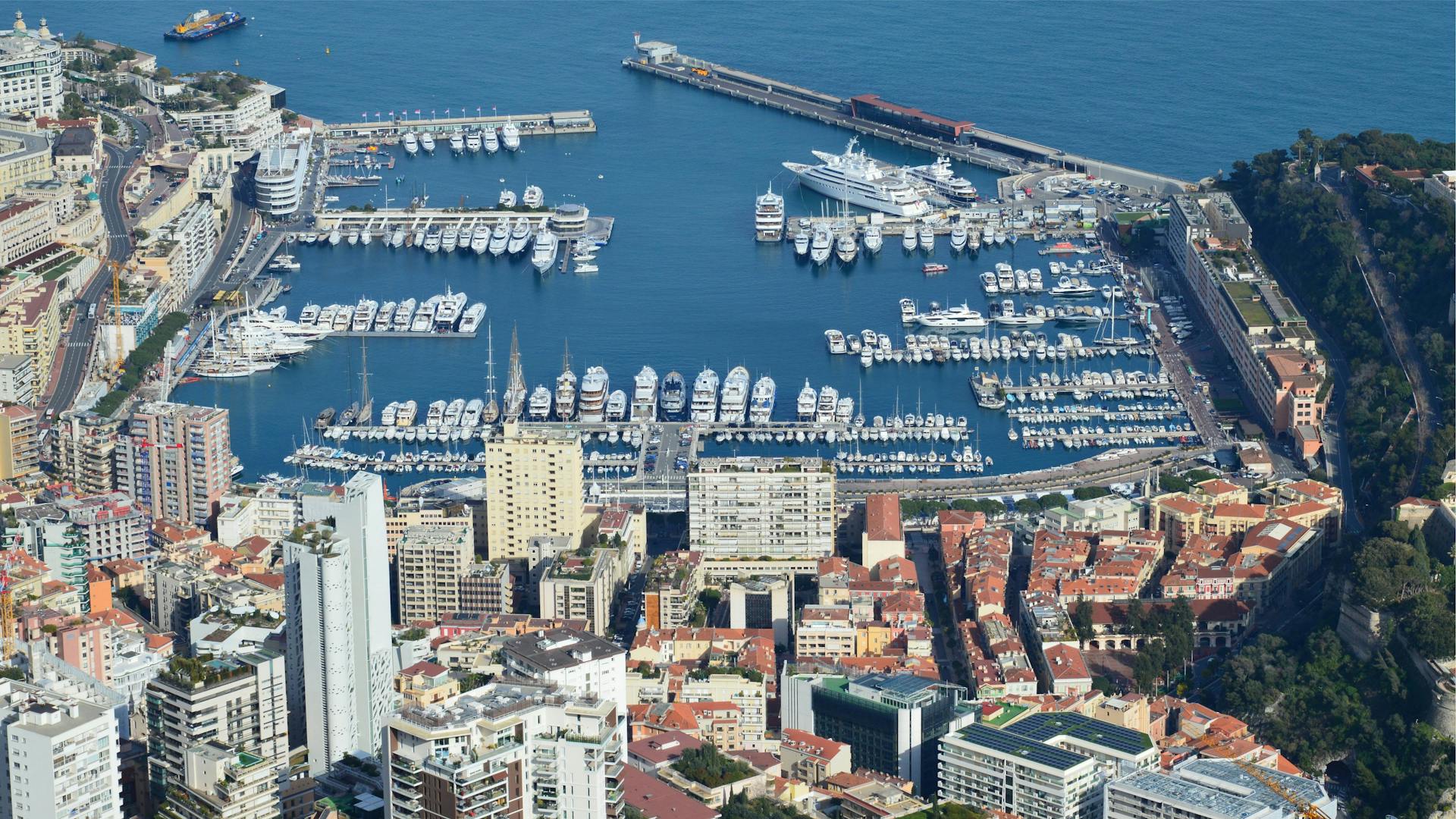 Stunning aerial view of Monaco harbor showcasing moored luxury yachts and cityscape.