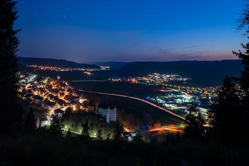 Free A serene night view of an illuminated town nestled in a valley, capturing the harmony of lights and night sky. Stock Photo