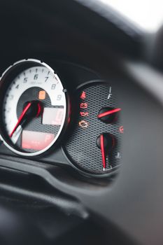 Close-up shot of illuminated car dashboard gauges with focus on speedometer and indicators.