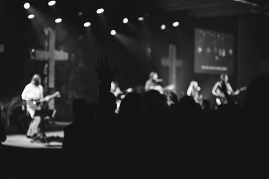 Silhouetted audience at a concert with musicians on stage and crosses in the background.