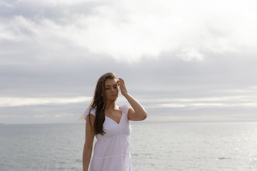 beyaz elbiseli kız, bulutlu gökyüzü, bulutlu gün içeren Ücretsiz stok fotoğraf