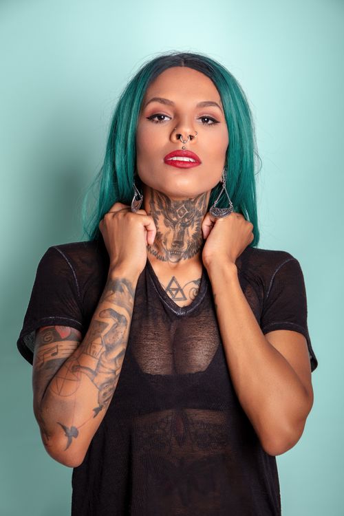 Free Vibrant studio portrait of a tattooed woman with green hair and piercings. Stock Photo