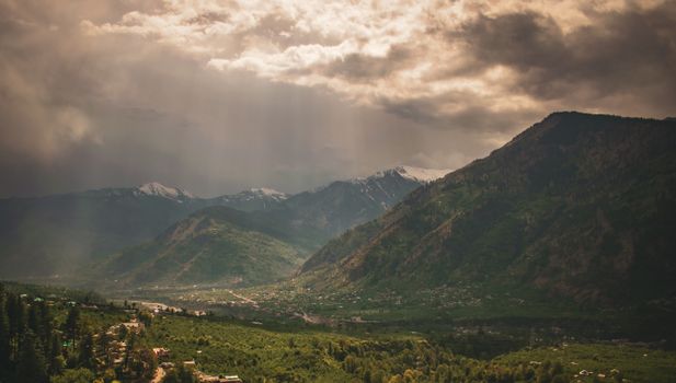 Breathtaking aerial view of misty mountains and valley in Manali, India, with dramatic clouds.