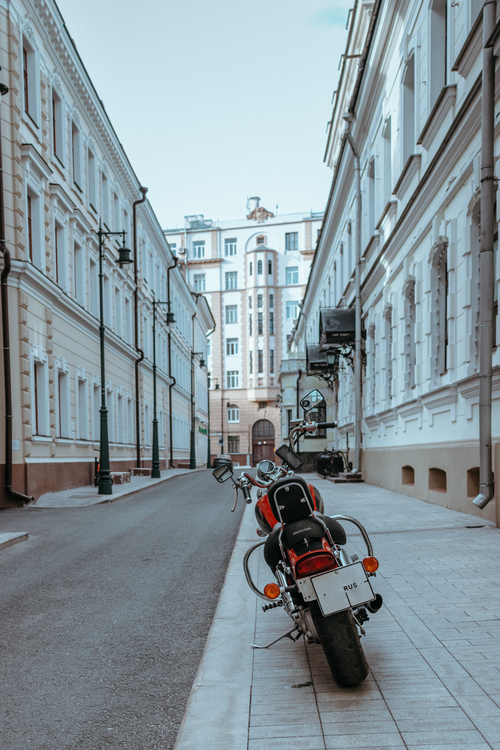 Free A serene street view with classic architecture and a parked motorcycle, ideal for travel or city themes. Stock Photo