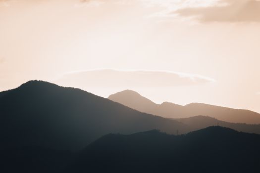 A tranquil scene of silhouetted mountains during sunset in İzmir, Turkey, with warm, peaceful tones.
