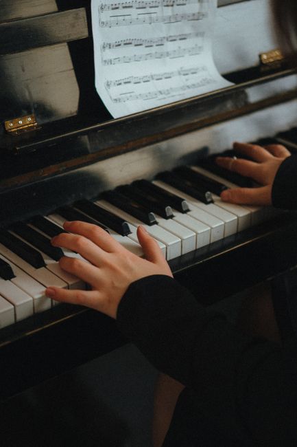 Hands playing piano with music sheet in view. Intimate and artistic setting.