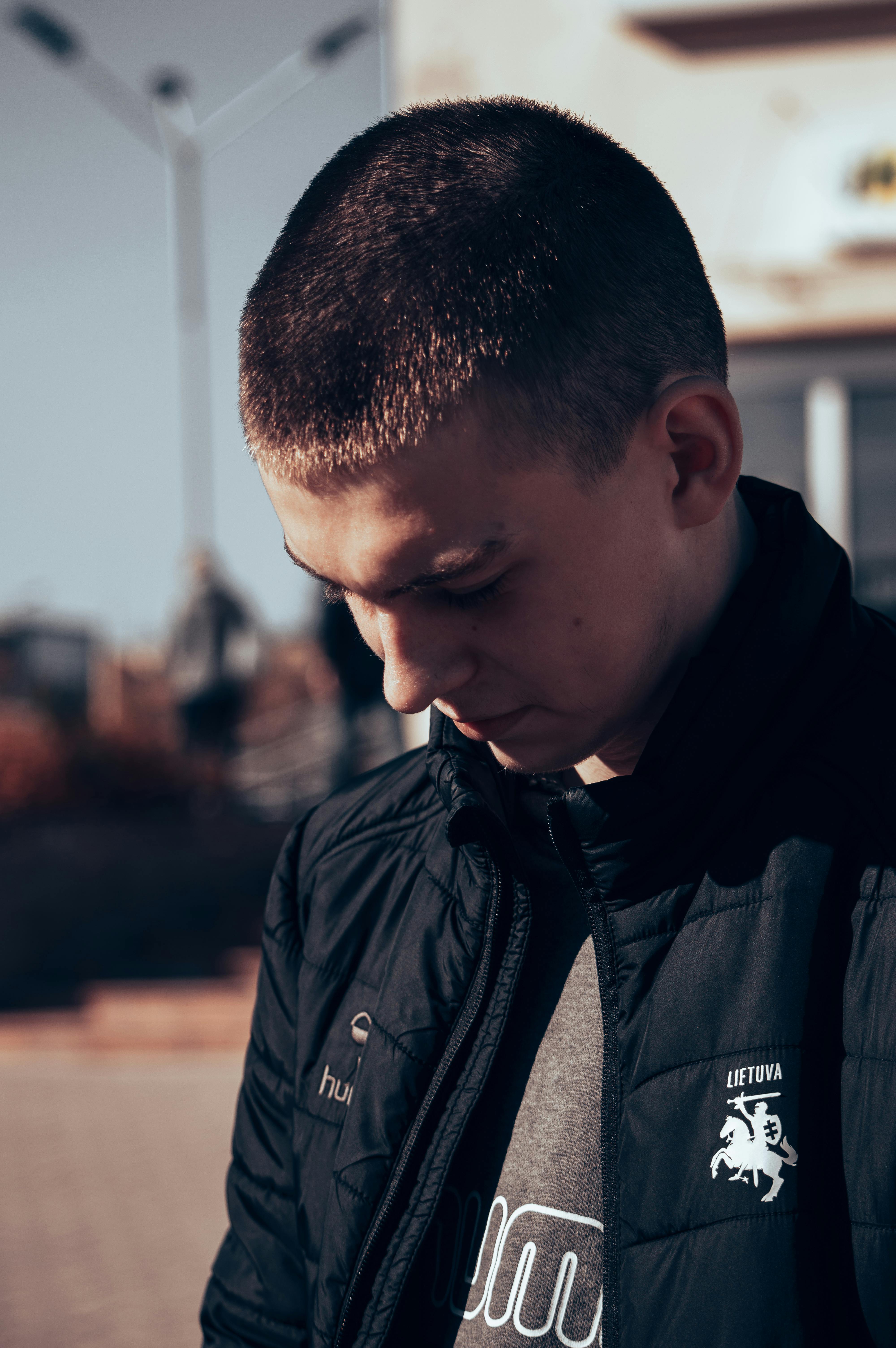 A young man in deep thought outdoors, showcasing a pensive mood in Lithuania.