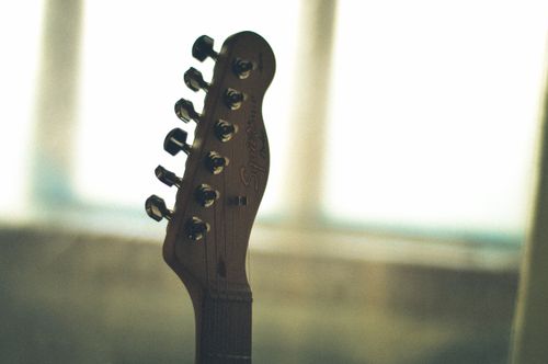 Free Detailed image of an electric guitar headstock with blurred background, showcasing tuning pegs and smooth wood finish. Stock Photo
