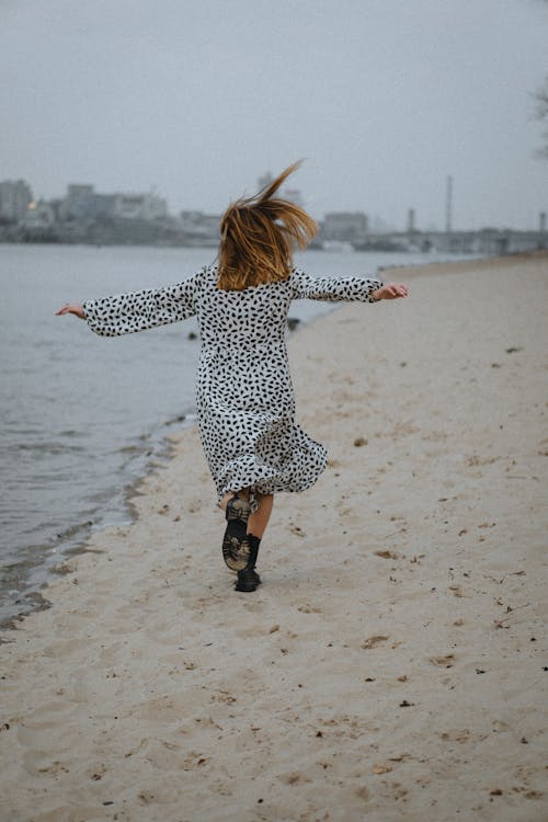 Free Woman Running Along the Beach with Arms Raised  Stock Photo